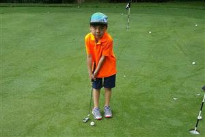 Young boy putting on a golf course.